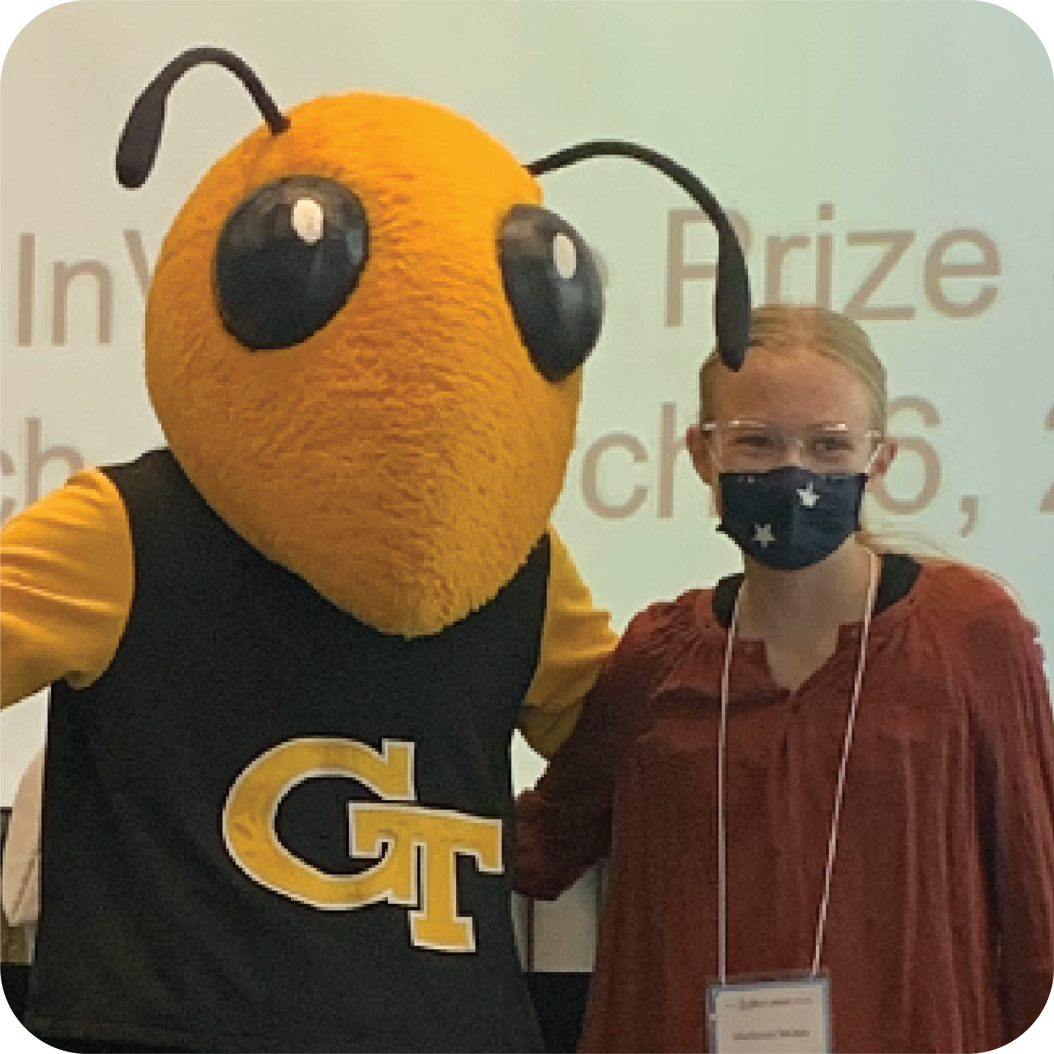 A smiling student standing next to Buzz (Georgia Tech's yellowjacket mascot).